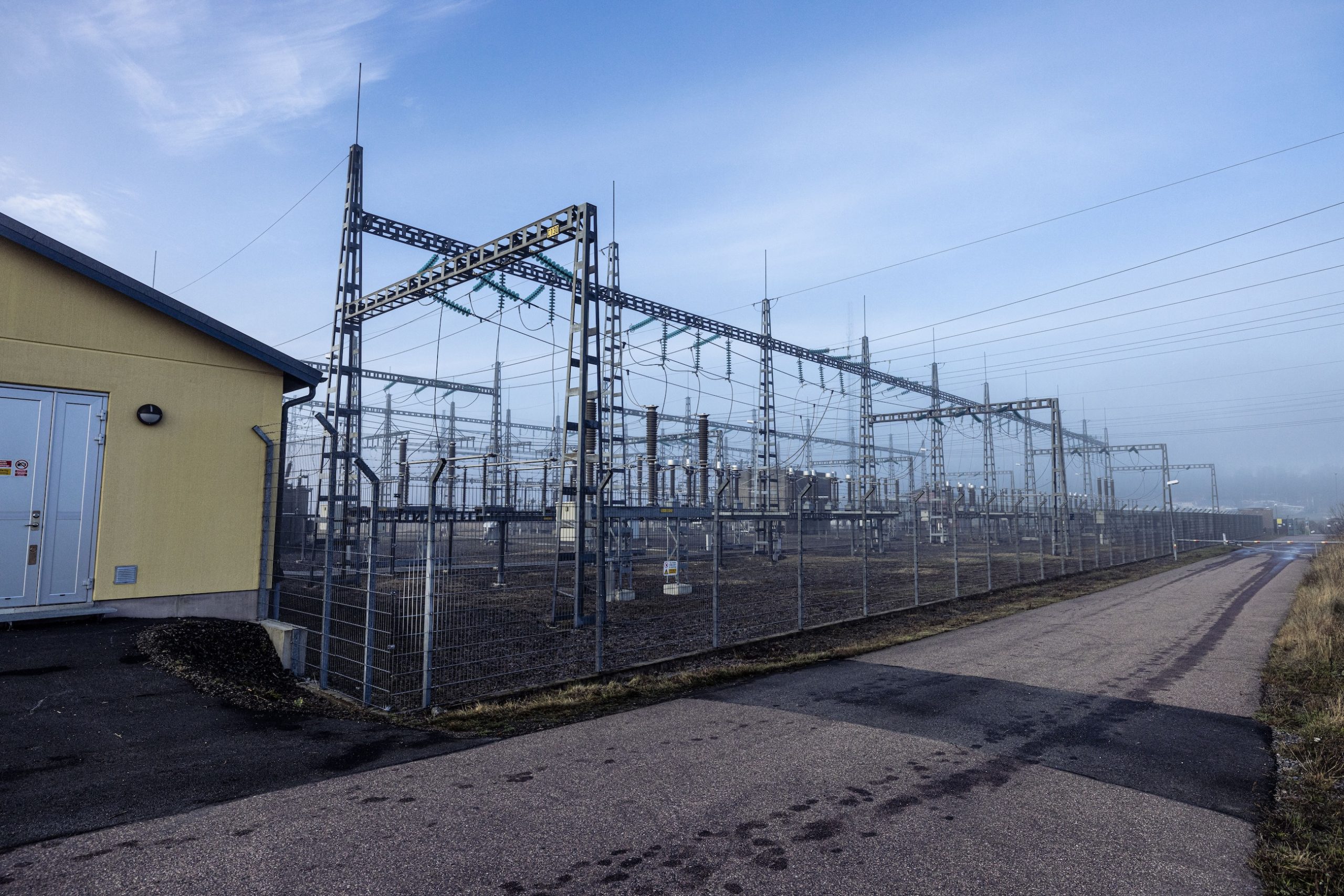 Substation building and overhead power lines crossing woodland